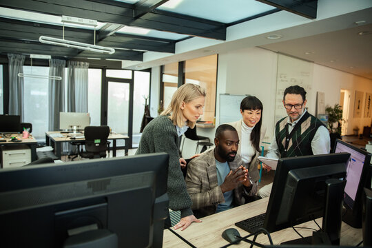 Diverse business team collaborating at computer in modern office