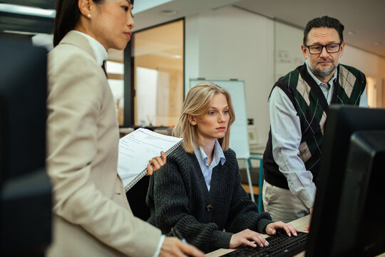 Colleagues reviewing a project on a desktop computer in a modern office