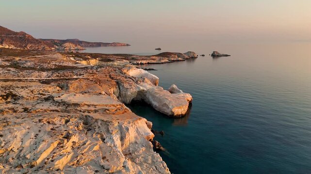 Early morning sunlight during a beautiful sunrise over the Aegean sea seen from the shore of Mandrakia on the Greek island Milos in Greece. Unique landscape on the coastline, natural blue ocean water