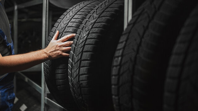 Tire at repairing service garage. Technician man replacing winter and summer tyre for safety road trip.