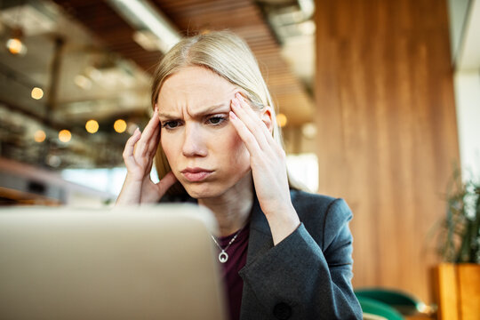 Stressed businesswoman working on laptop in cafe