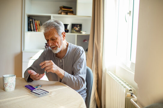 Senior man taking daily medication at home