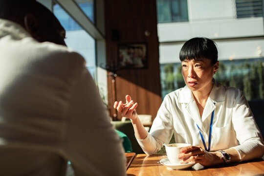 Two professionals discussing work over coffee in a cafe