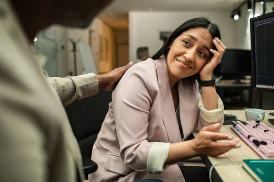Coworker comforting stressed colleague at office desk