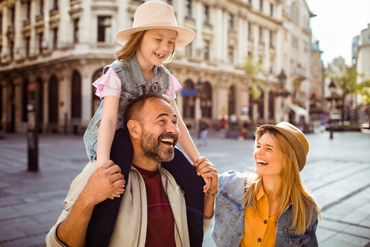 Smiling parents with daughter sightseeing in historic european city