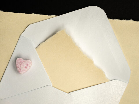 Open Envelope With Torn Paper Note and Pink Heart Candy for Valentine Love Message