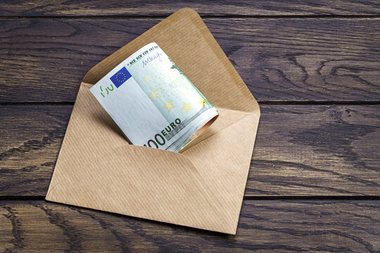 Money tucked inside envelope on wooden table