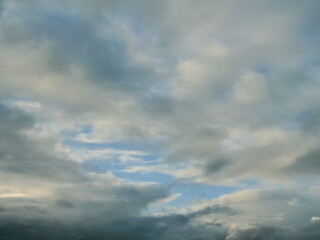 Obraz premium Dense clouds swirl across the sky, hinting at impending rain. Soft blue breaks through, offering subtle relief. Mood feels tense yet serene, like nature's quiet pause