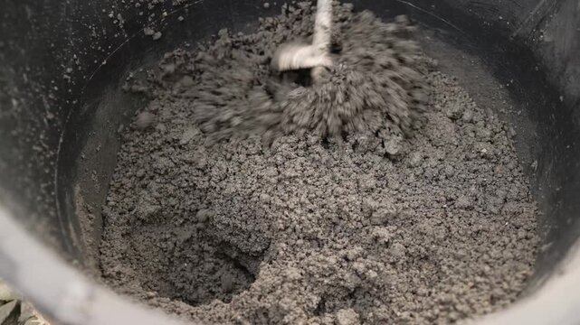 High angle view of manual labor process. Preparation of mortar for building or renovation project. Industrial background with earthy tones and natural light. DIY home improvement concept
