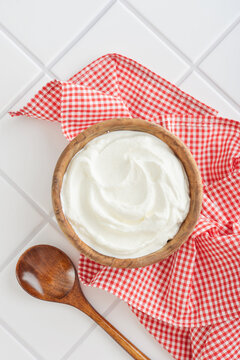 Sour cream in a wooden bowl with a wooden spoon