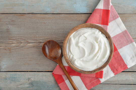Sour cream in a wooden bowl with a wooden spoon