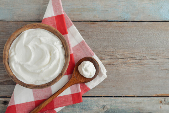 Sour cream in a wooden bowl with a wooden spoon