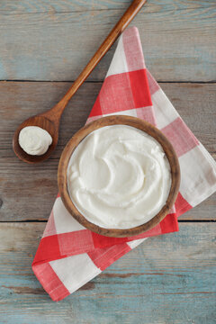 Sour cream in a wooden bowl with a wooden spoon