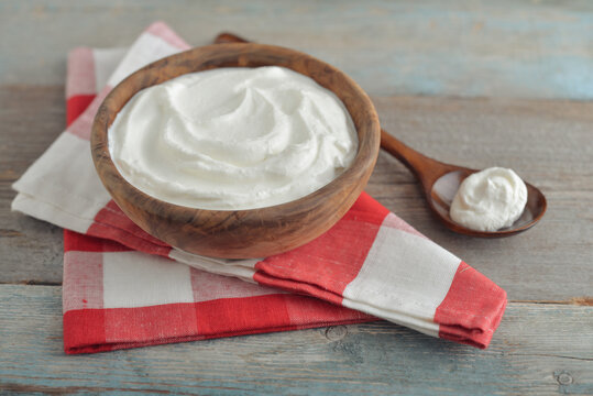 Sour cream in a wooden bowl with a wooden spoon