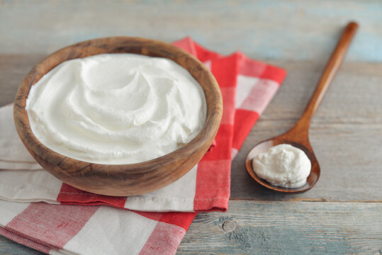 Sour cream in a wooden bowl with a wooden spoon