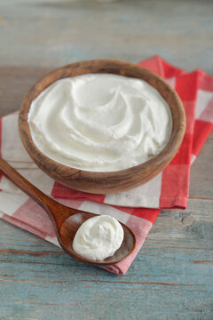 Sour cream in a wooden bowl with a wooden spoon