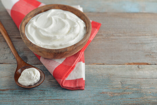 Sour cream in a wooden bowl with a wooden spoon