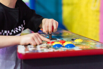 Child hands playing on vintage arcade machine control panel with joystick and buttons © Matico