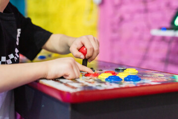 Child hands playing on vintage arcade machine control panel with joystick and buttons © Matico
