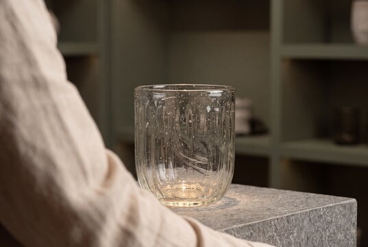 Artisan Textured Glass Tumbler with Tiny Bubbles Standing on Stone Pedestal in Elegant Interior