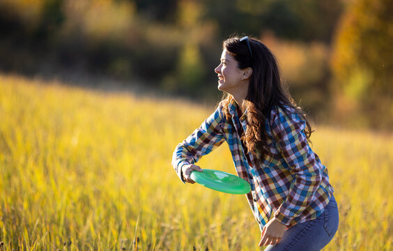 Woman throws frisbee in a field during golden hour