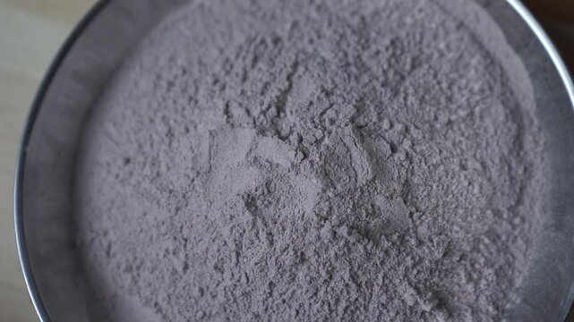 Close up of cocoa powder in a metal bowl seen from above