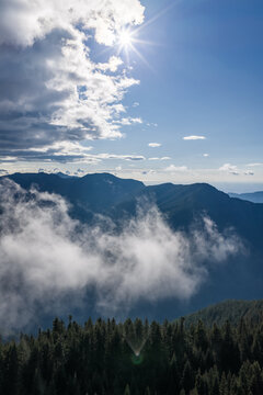 Sunlit Mountain Peaks and Misty Clouds Over Forested Ridge Near Chilliwack BC Canada