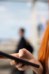 Close-up tourist holds a mobile phone in an airport terminal while checking in online, using a smartphone to access airline information and review a plane timetable during air travel. © DC Studio