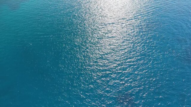 Sparkling blue sea surface with a bright band of sunlight glittering across gentle ripples, top down water texture background, aqua and teal gradient, abstract ocean pattern for summer designs and ca