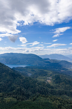 Blue Sky Over Forested Mountains and Lake Near Chilliwack BC Canada With Puffy Clouds