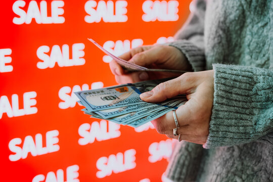 Person holding US dollar banknotes during sale shopping.