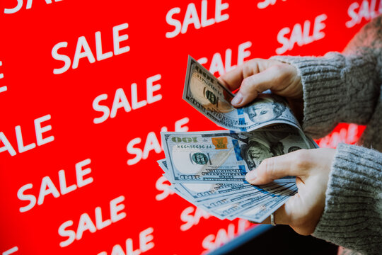 Person holding US dollar banknotes during sale shopping.