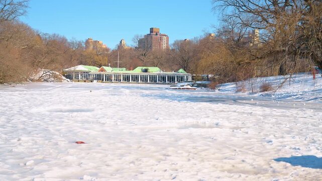View on the historic Loeb Boathouse in Central Park, New York City, USA. Snow-covered scenery on winter day.