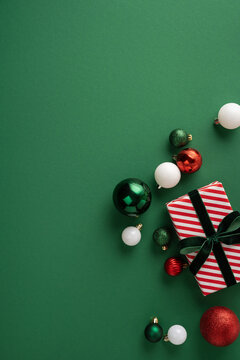 Festive Christmas gift and ornaments with striped wrapping and baubles for Merry New Year celebration on vertical green blank space