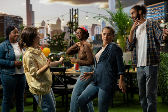 Women dance and socialize with friends at urban rooftop barbecue