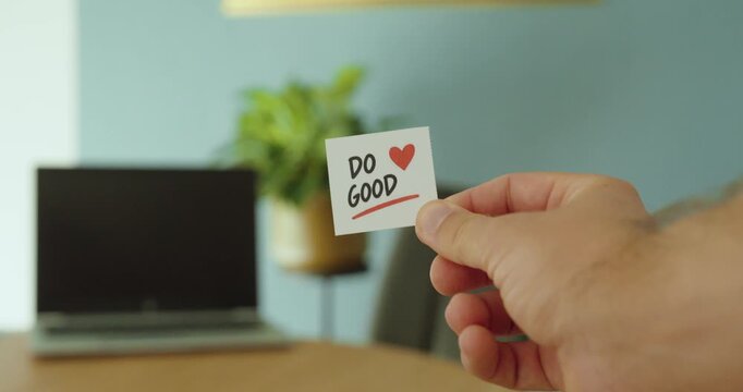 Close-up of a hand holding a &ldquo;Do Good&rdquo; card with heart symbol, representing kindness, compassion, positive action and helping others.