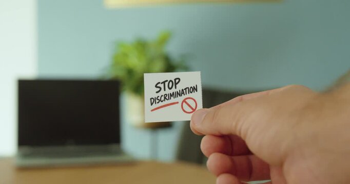 Close-up of a hand holding a &ldquo;Stop Discrimination&rdquo; card, representing equality, inclusion, human rights and anti-discrimination awareness.
