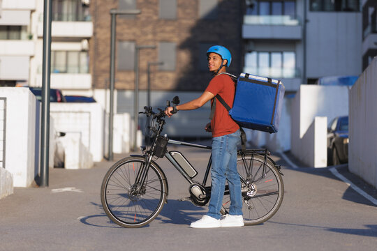 Delivery courier with electric bike waits in the city street