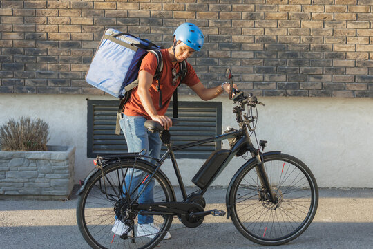 Gig economy and food delivery, courier with e-bike and thermal backpack