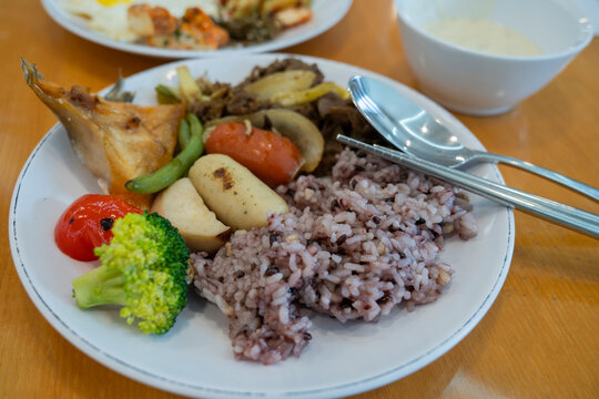 Korean hotel breakfast buffet plate served with multigrain purple rice, beef bulgogi, grilled salmon and fresh vegetables.