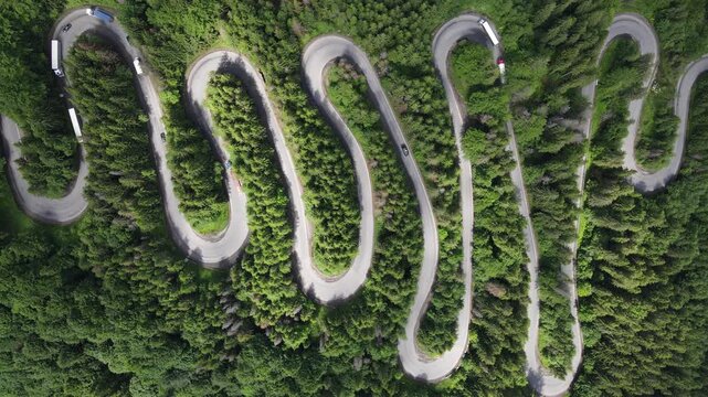 Aerial view of a winding serpentine road winding through a dense green forest, pass road, Bratocea Pass, Carpathians, Great Wallachia, Romania