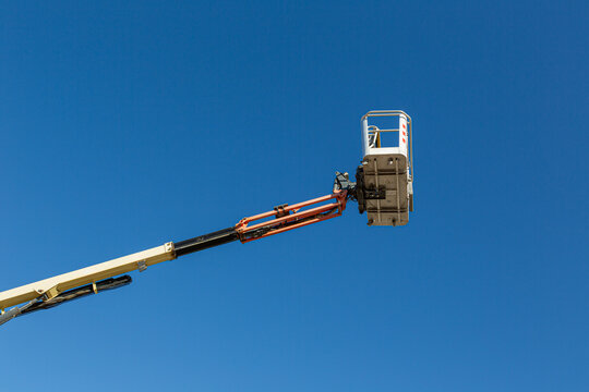Aerial Work Platform Bucket for Construction and Maintenance Services into Clear Blue Sky. Telescopic, boom, lift, basket, aerial, work, equipment, machinery, outdoors, copy space, maintenance, repair