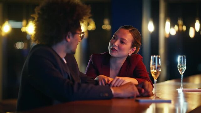 Multiracial coworkers joking champagne bar counter. Woman laughing lounge night.
