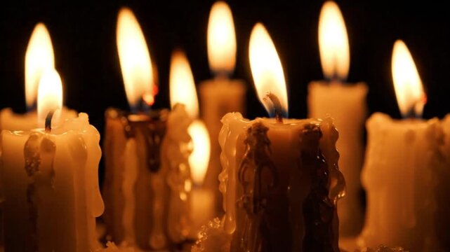 Grid pattern of lit candles with flickering flames and dripping wax