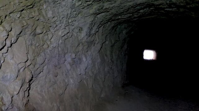 Close-up camera panning over rough cave wall revealing colorful mineral deposit build-up and dark tunnel passage.