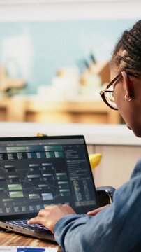 Vertical screen: Woman focuses on programming and software development while laptop screen displays code, scripts and binary data for system maintenance during remote work.