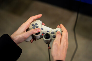 Hands holding retro game controller gamepad playing video game console indoors, representing gaming leisure, esports, and interactive digital entertainment. © Marina