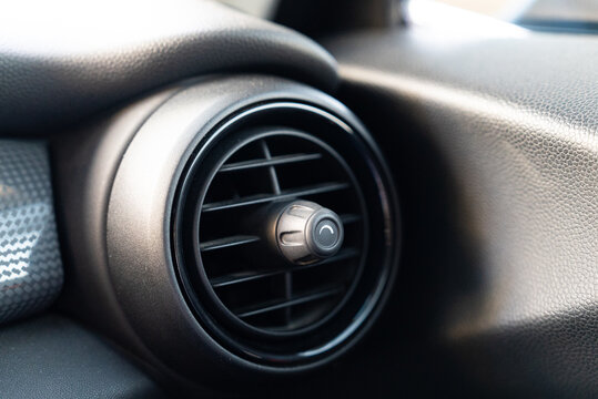 Close up of car air vent with dust particles in sunlight on dashboard interior