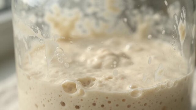 Active Sourdough Starter Fermenting with Bubbles in Glass Jar