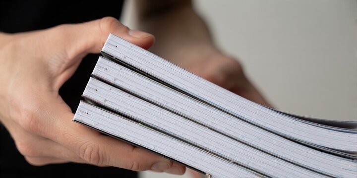 Woman holding a stack of newly printed paperback notebooks or journals for school or work representation
